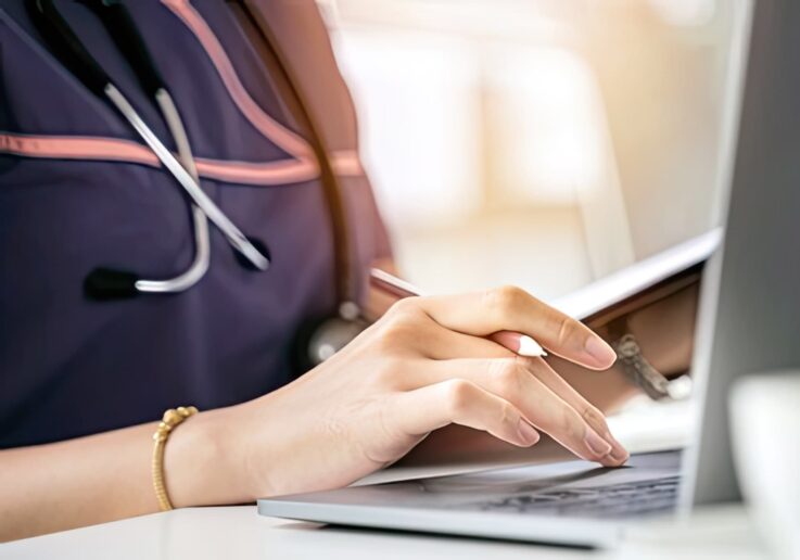 a nurse sits at a desk using a laptop